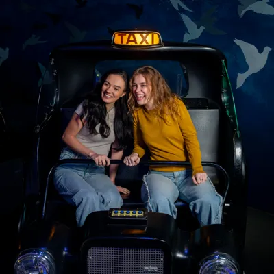 Two people sitting in in the taxi cab of the Spirit of London ride at Madame Tussauds London