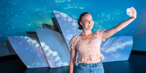 Madame Tussauds Sydney Guest Smiling Taking A Selfie In Front Of The Sydney Opera House